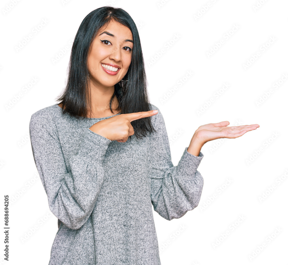 Beautiful asian young woman wearing casual clothes amazed and smiling to the camera while presenting with hand and pointing with finger. Beautiful asian young woman wearing casual clothes amazed and smiling to the camera while presenting with hand and pointing with finger.