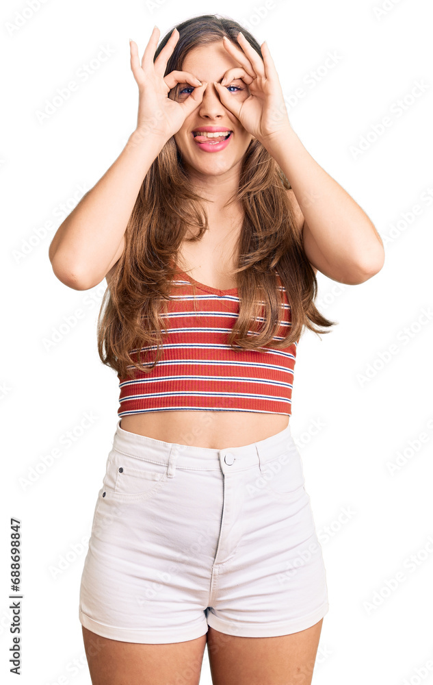 Beautiful caucasian young woman wearing casual clothes doing ok gesture like binoculars sticking tongue out, eyes looking through fingers. crazy expression. Beautiful caucasian young woman wearing casual clothes doing ok gesture like binoculars sticking tongue out, eyes looking through fingers. crazy expression.