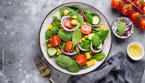 spring vegan salad with spinach cherry tomatoes corn salad baby spinach cucumber and red onion healthy food concept gray stone table top view copy space © Charlotte