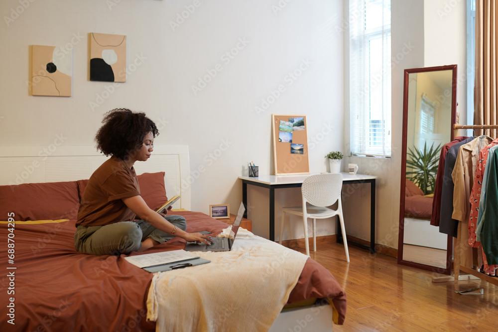 Freelance UI designer sitting on bed and reading brief from client before starting work on mobile app interface Freelance UI designer sitting on bed and reading brief from client before starting work on mobile app interface