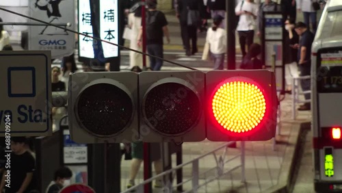 TOKYO, JAPAN - NOV 2023 : Close up shot of led traffic light at the street in night time. Crowd of people walking in background. Japanese traffic and transportation concept video. 4K time lapse shot. photo