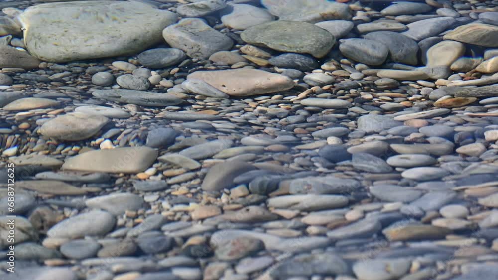 Clear transparent water of the Mediterranean shore flowing over colorful little stones on a beach in Samos Clear transparent water of the Mediterranean shore flowing over colorful little stones on a beach in Samos