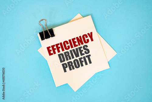 Text EFFICIENCY DRIVES PROFIT on sticky notes with copy space and paper clip isolated on red background. Finance and economics concept.