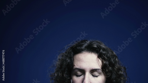 Young woman closing eyes in meditation and relaxation on blue backdrop  person forehead with top space of screen available for animation