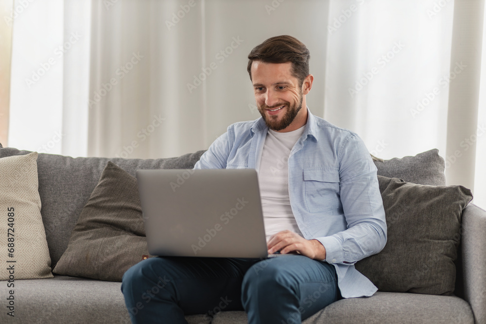 Man entrepreneur seamlessly blending work and home life as he tackles business tasks online using laptop from the comfort of his living room at home Man entrepreneur seamlessly blending work and home life as he tackles business tasks online using laptop from the comfort of his living room at home