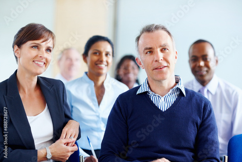 Businesspeople, audience and listen to presentation at conference, workshop or seminar in New York. Diverse group, man and woman with excited expression for discussion, speaker or panel in boardroom
