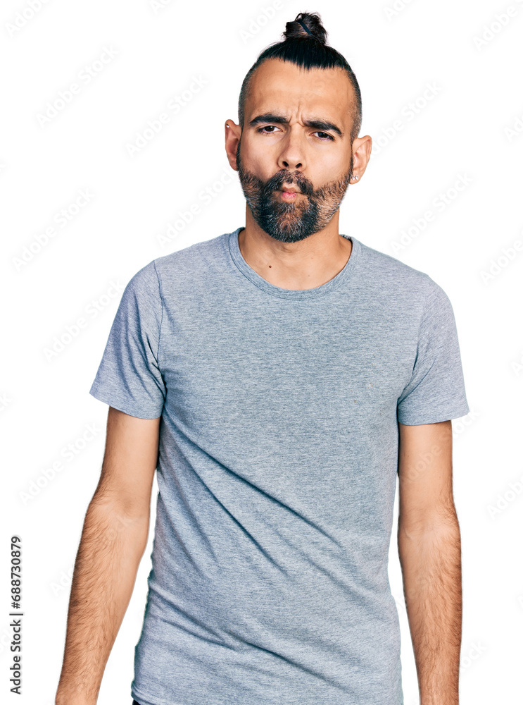 Hispanic man with ponytail wearing casual grey t shirt making fish face with lips, crazy and comical gesture. funny expression. Hispanic man with ponytail wearing casual grey t shirt making fish face with lips, crazy and comical gesture. funny expression.