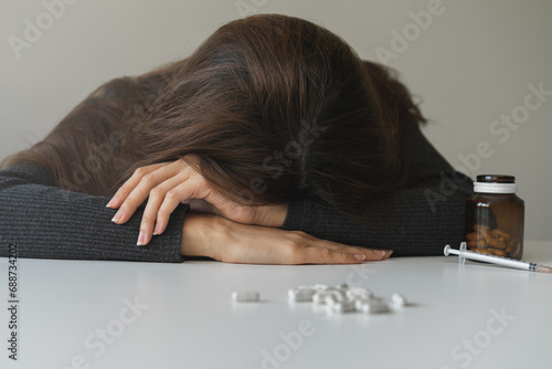 Pills, medication with narcotic syringe on table asian young woman fall asleep lying at home, abuse overdose. Sick pain of health, unhealthy. Suicide depressed or despair, anti drugs, drug addict. photo