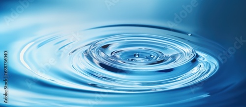 Closeup macro transparent water drop with ripples and waves isolated on a blue background