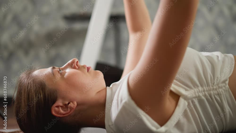 Woman raises arms with dumbbells in hands. Committed sports enthusiast dedicates herself to sculpting arm muscles using weights in home fitness space Woman raises arms with dumbbells in hands. Committed sports enthusiast dedicates herself to sculpting arm muscles using weights in home fitness space