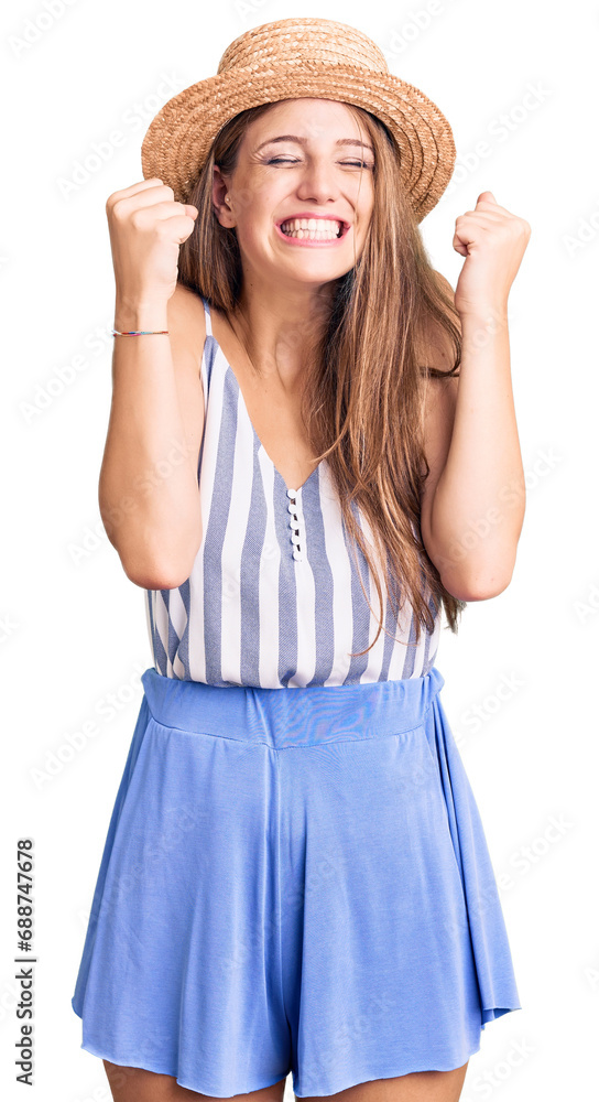 Young beautiful blonde woman wearing summer hat excited for success with arms raised and eyes closed celebrating victory smiling. winner concept. Young beautiful blonde woman wearing summer hat excited for success with arms raised and eyes closed celebrating victory smiling. winner concept.