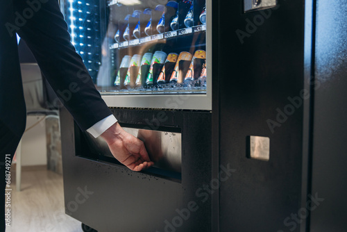 Close up hand of man pushing button on vending machine for choosing a snack or drink. Small business and consumption concept.