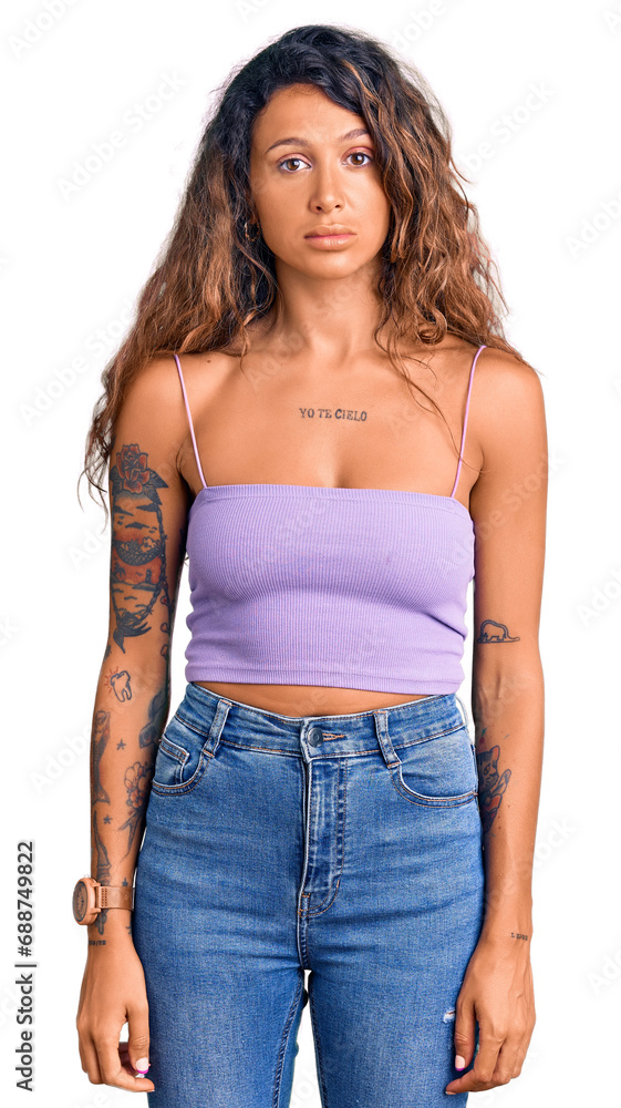 Young hispanic woman with tattoo wearing casual clothes relaxed with serious expression on face. simple and natural looking at the camera. Young hispanic woman with tattoo wearing casual clothes relaxed with serious expression on face. simple and natural looking at the camera.