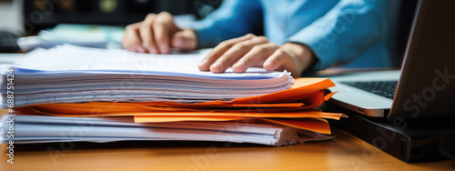 Close-up of a man working with a stack of documents and reports on his office desk photo