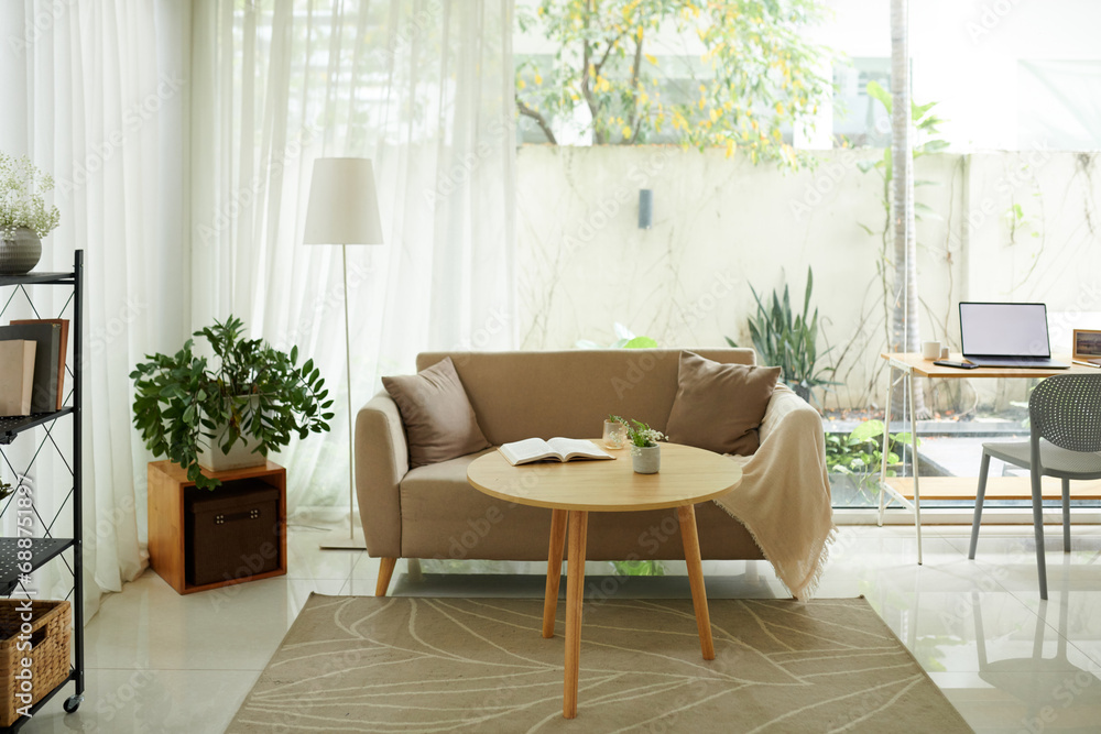 Fototapeta premium Small wooden coffee table next to comfy couch in living room