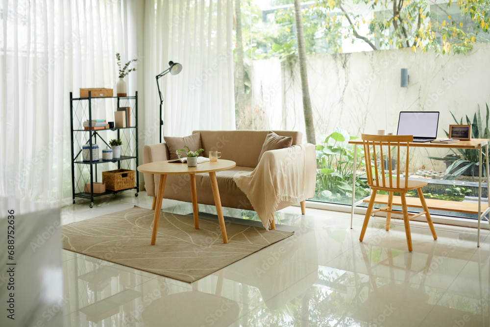 Fototapeta premium Light spacious living room area with couch, coffee table, and desk for work