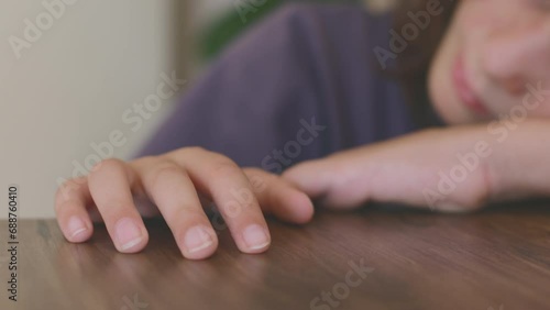 child's hand close-up. A little boy is sitting at the table, tapping his fingers on the tabletop, the first grader is overtired from studying, the student is stressed, sleeping at the table. photo