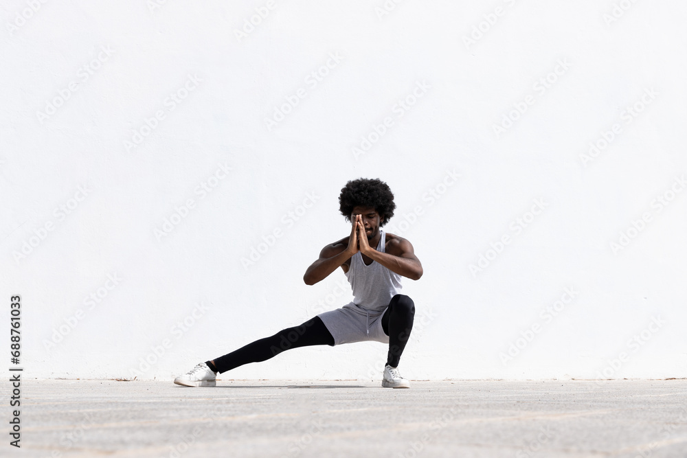 Serious black sportsman exercising over white wall Serious black sportsman exercising over white wall