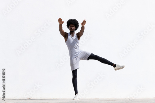 Serious black man stretching body over white wall photo