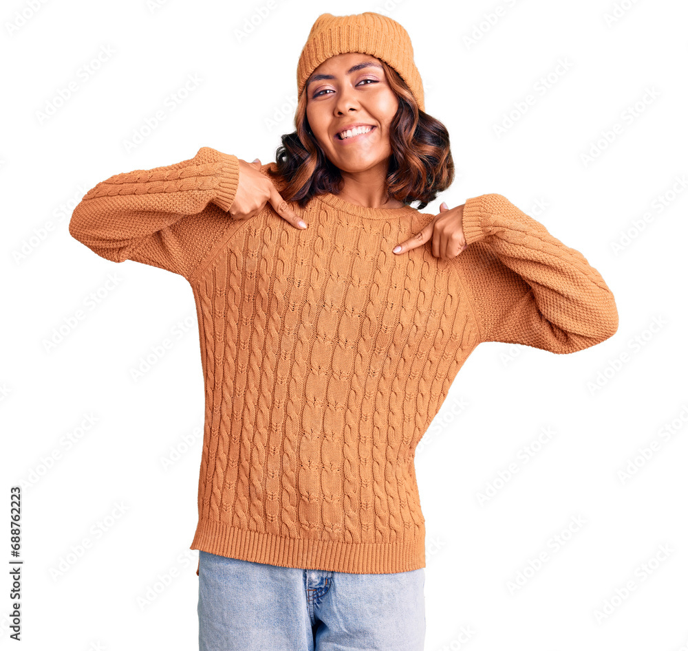 Young beautiful mixed race woman wearing wool sweater and winter hat looking confident with smile on face, pointing oneself with fingers proud and happy. Young beautiful mixed race woman wearing wool sweater and winter hat looking confident with smile on face, pointing oneself with fingers proud and happy.