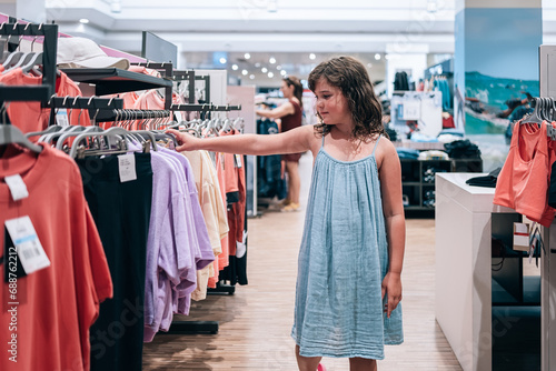 Girl choosing clothes at store photo