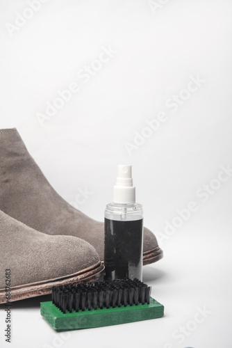Gray suede boots and water protection spray  brush on white background. Shoe care