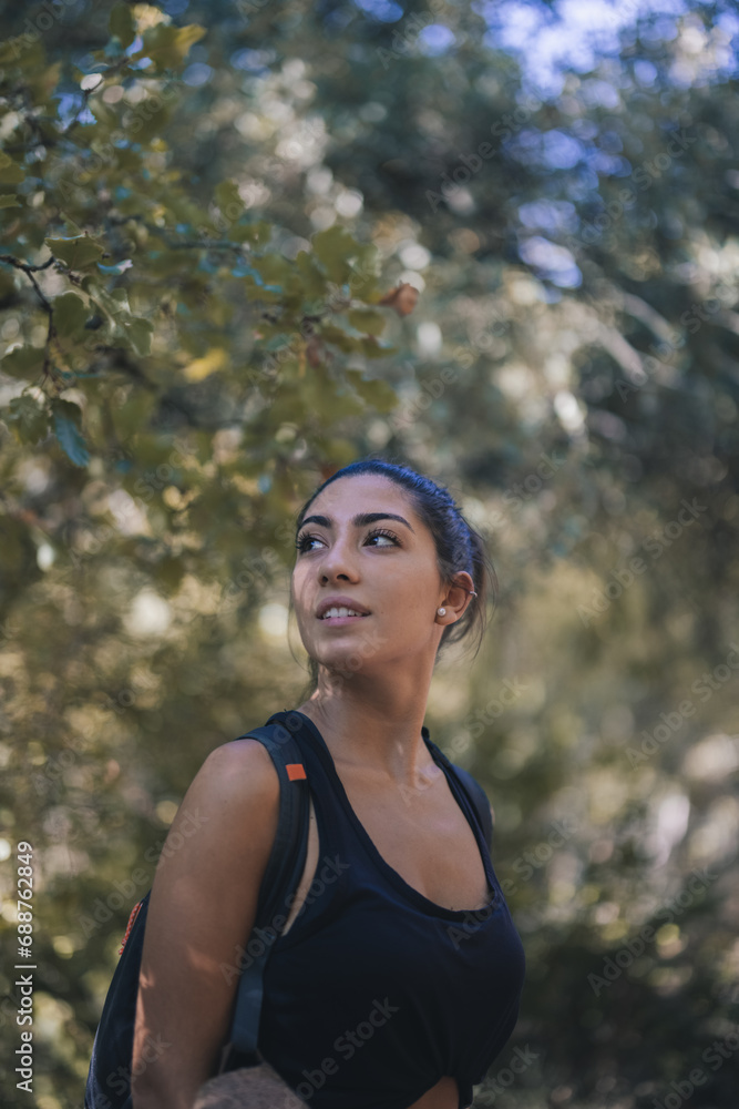 Serene woman looking away while hiking in forest Serene woman looking away while hiking in forest