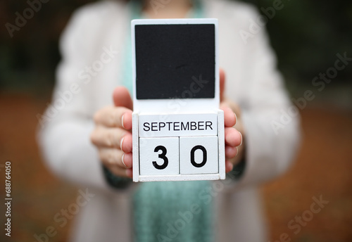 Woman holds calendar with the date september 30 outdoors. photo