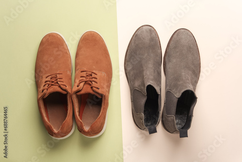 Two pairs of suede men's shoes on a green beige background. Top view