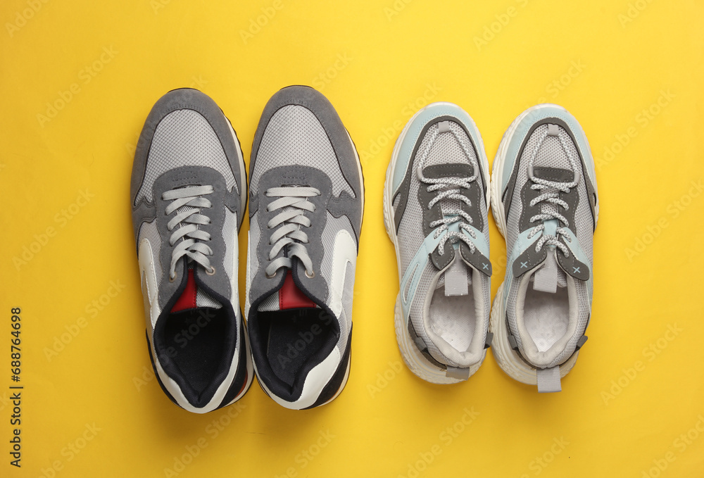 Male and female pair of sports shoes for running on a yellow background Male and female pair of sports shoes for running on a yellow background