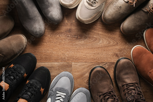 Different pairs of shoes on the wooden floor. Top view. Copy space
