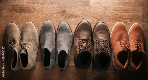 Different pairs of shoes on the wooden floor. Top view.