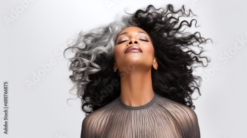 Senior Chic: Black Mid-aged Model with Afro-Gray Hair in Windy Shoot, Eyes Closed Against Clear Background, Great for Hairstyling, Makeup Services, Fashion, and Beauty Sector