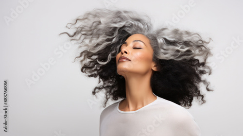 Graceful Aging: Mid-aged Black Model with Afro Gray Hair Poses, Wind-Swept Hair, Closed Eyes, Ideal for Promoting Makeup, Hairstyling Services, Fashion, and Cosmetic Industry for All Ages