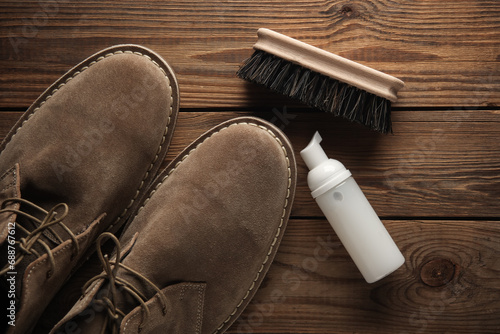 Suede shoes with cleaning foam and brush on wooden background. Shoe care