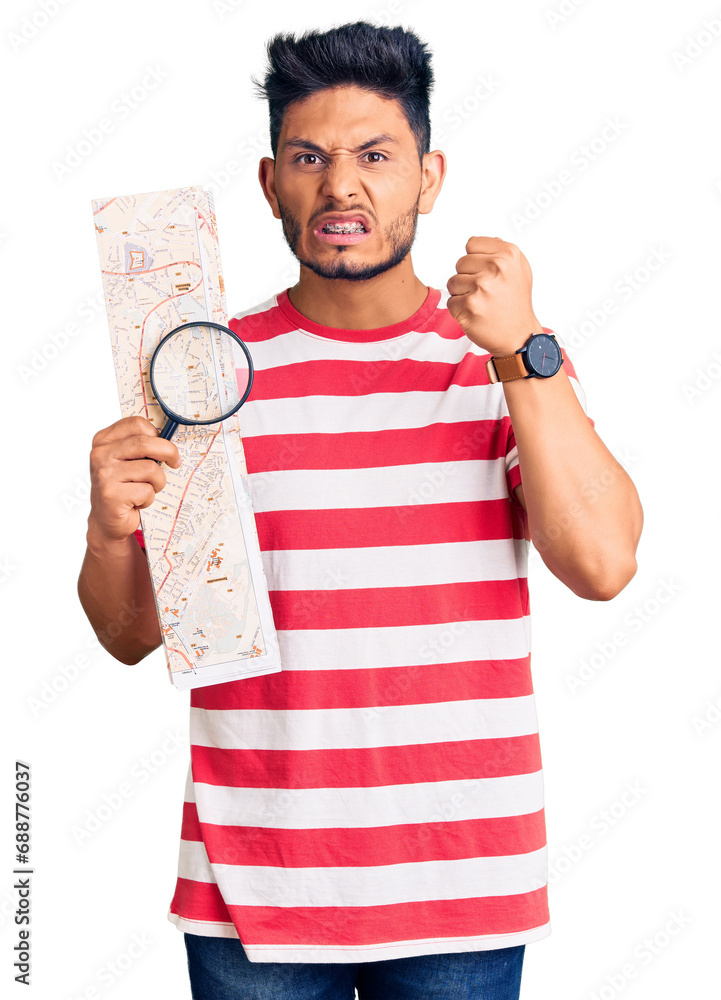 Handsome latin american young man looking at city map with magnifying glass annoyed and frustrated shouting with anger, yelling crazy with anger and hand raised Handsome latin american young man looking at city map with magnifying glass annoyed and frustrated shouting with anger, yelling crazy with anger and hand raised