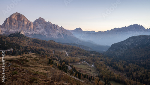 View on beautiful alpine valley during autumn sunrise with fog and golden larches, Dolomites, Italy
