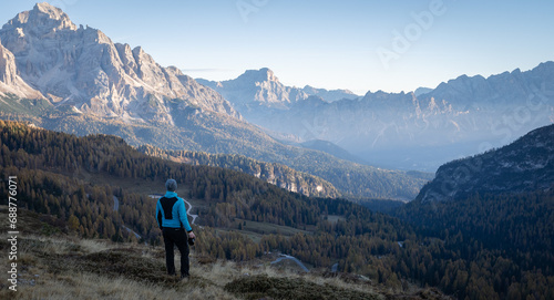 Man with camera enjoying views on beautiful mountain valley during early morning, Dolomites, Italy