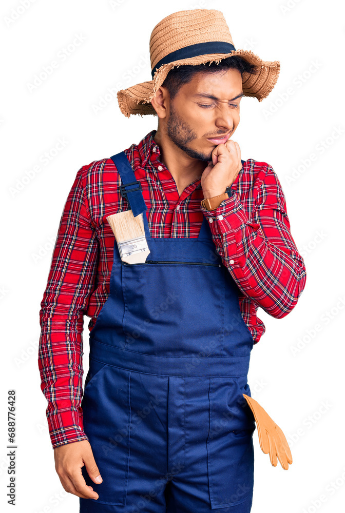 Handsome latin american young man weaing handyman uniform touching mouth with hand with painful expression because of toothache or dental illness on teeth. dentist