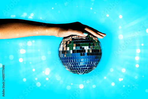 Woman holding disco ball against illuminated background photo