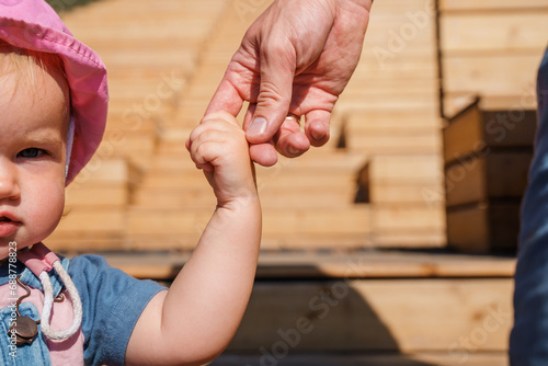 The father holds the hand of the toddler child, two hands
