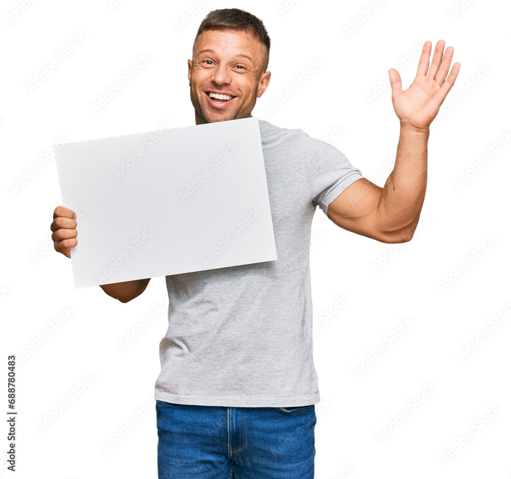 Handsome muscle man holding blank empty banner celebrating victory with happy smile and winner expression with raised hands Handsome muscle man holding blank empty banner celebrating victory with happy smile and winner expression with raised hands