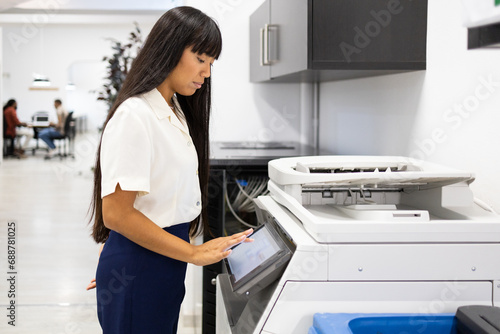 Positive businesswoman using modern copier in office photo