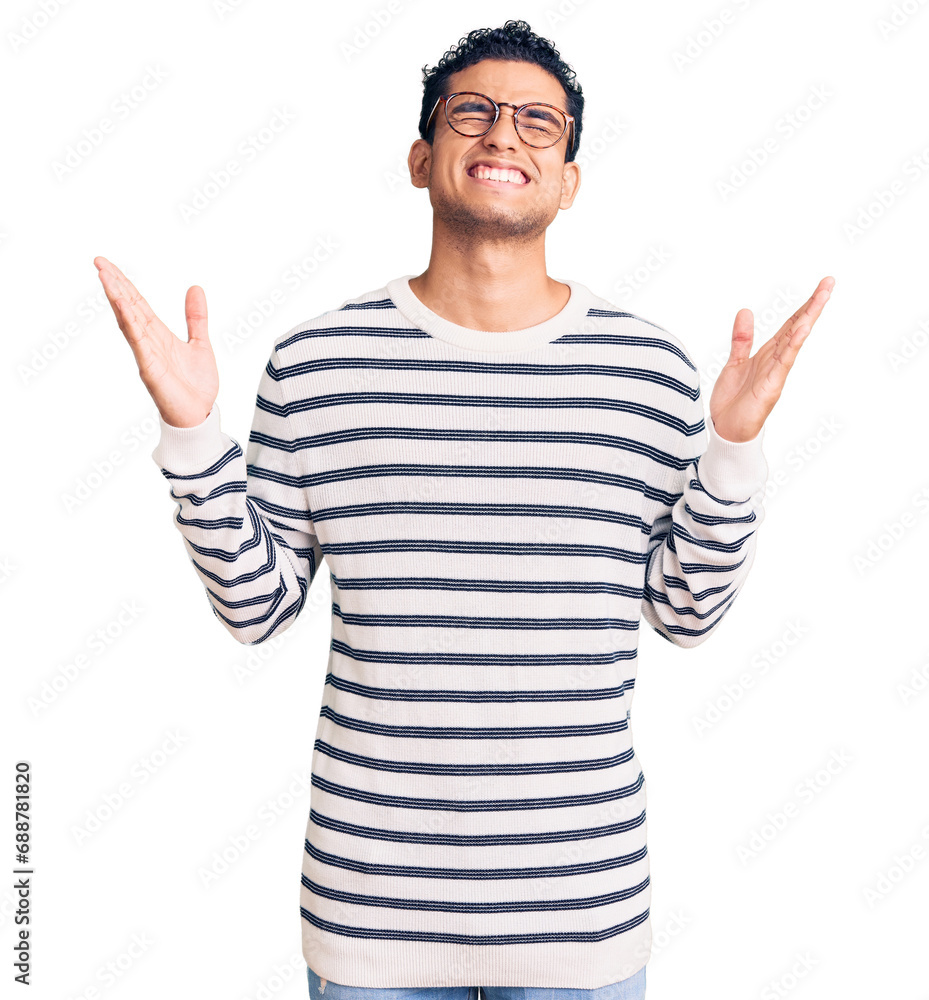 Hispanic handsome young man wearing casual clothes and glasses celebrating mad and crazy for success with arms raised and closed eyes screaming excited. winner concept Hispanic handsome young man wearing casual clothes and glasses celebrating mad and crazy for success with arms raised and closed eyes screaming excited. winner concept