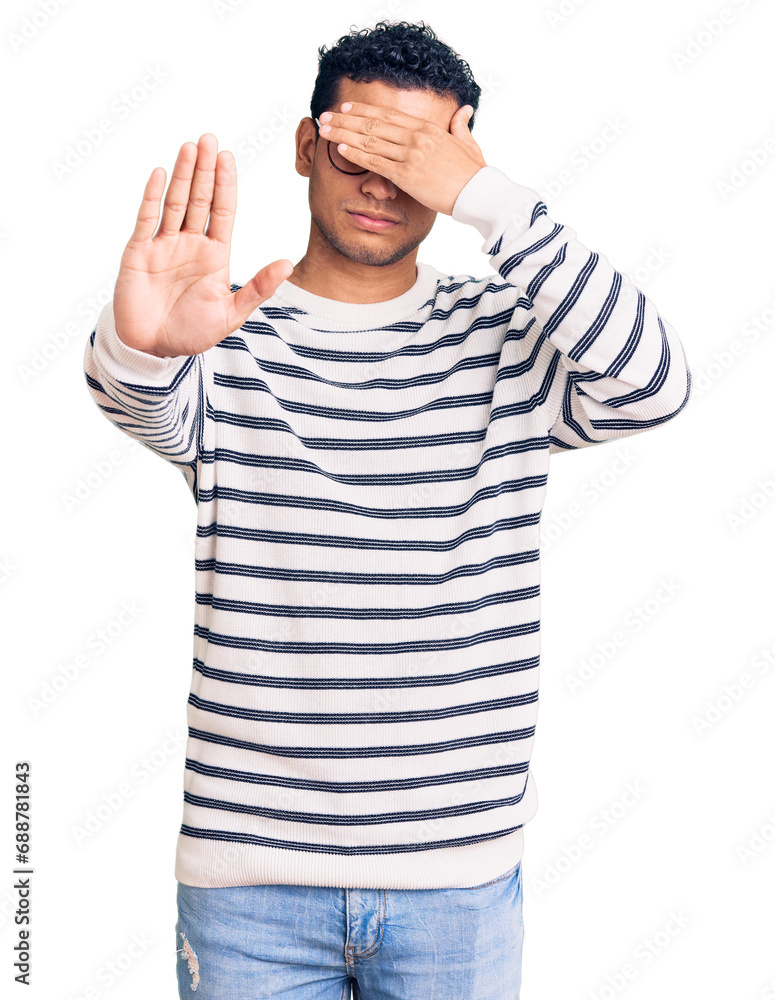 Hispanic handsome young man wearing casual clothes and glasses covering eyes with hands and doing stop gesture with sad and fear expression. embarrassed and negative concept. Hispanic handsome young man wearing casual clothes and glasses covering eyes with hands and doing stop gesture with sad and fear expression. embarrassed and negative concept.