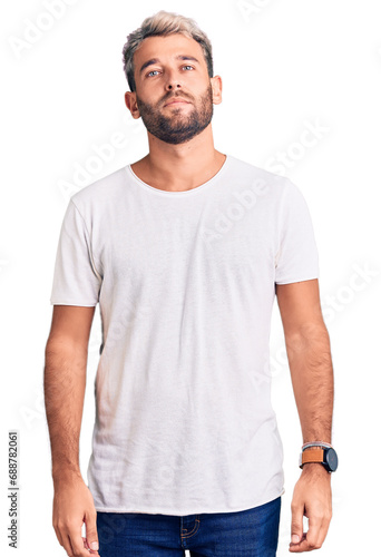 Young handsome blond man wearing casual t-shirt skeptic and nervous, disapproving expression on face with crossed arms. negative person.