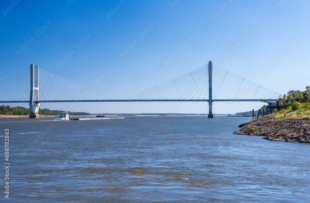 Modern cable-stayed suspension bridge, the Jesse Brent Memorial bridge across the Mississippi river near Greenville with river barge