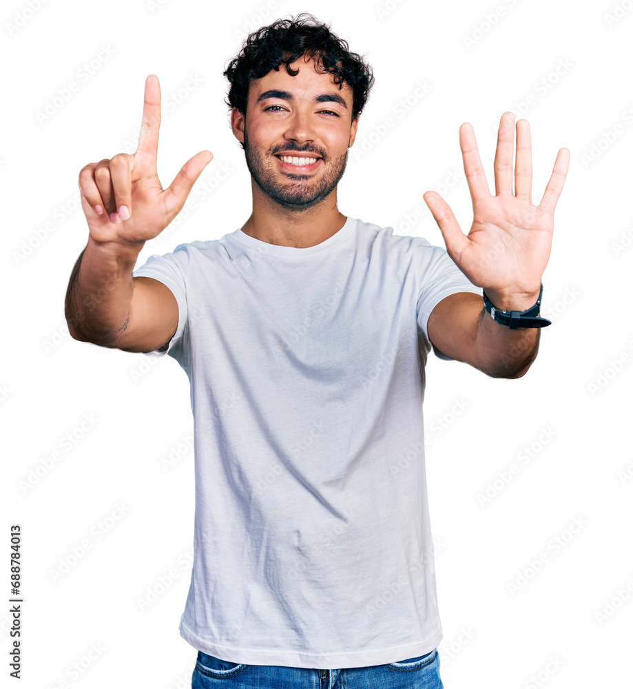 Hispanic young man with beard wearing casual white t shirt showing and pointing up with fingers number seven while smiling confident and happy. Hispanic young man with beard wearing casual white t shirt showing and pointing up with fingers number seven while smiling confident and happy.