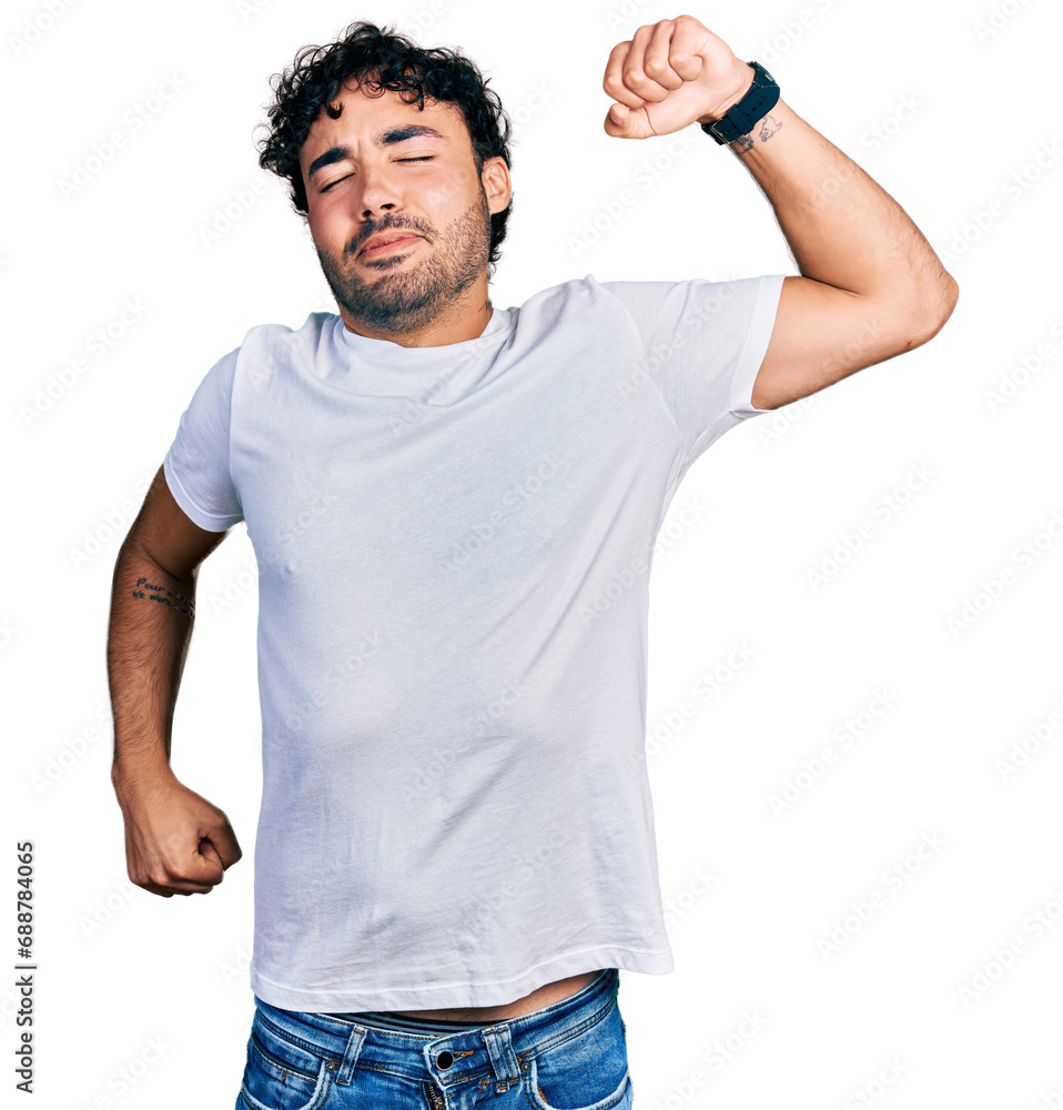 Hispanic young man with beard wearing casual white t shirt stretching back, tired and relaxed, sleepy and yawning for early morning Hispanic young man with beard wearing casual white t shirt stretching back, tired and relaxed, sleepy and yawning for early morning