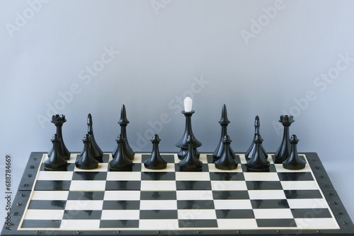 Black chess pieces stand on the board without a king. Absence of a leader, position uncertainty, leaderless photo